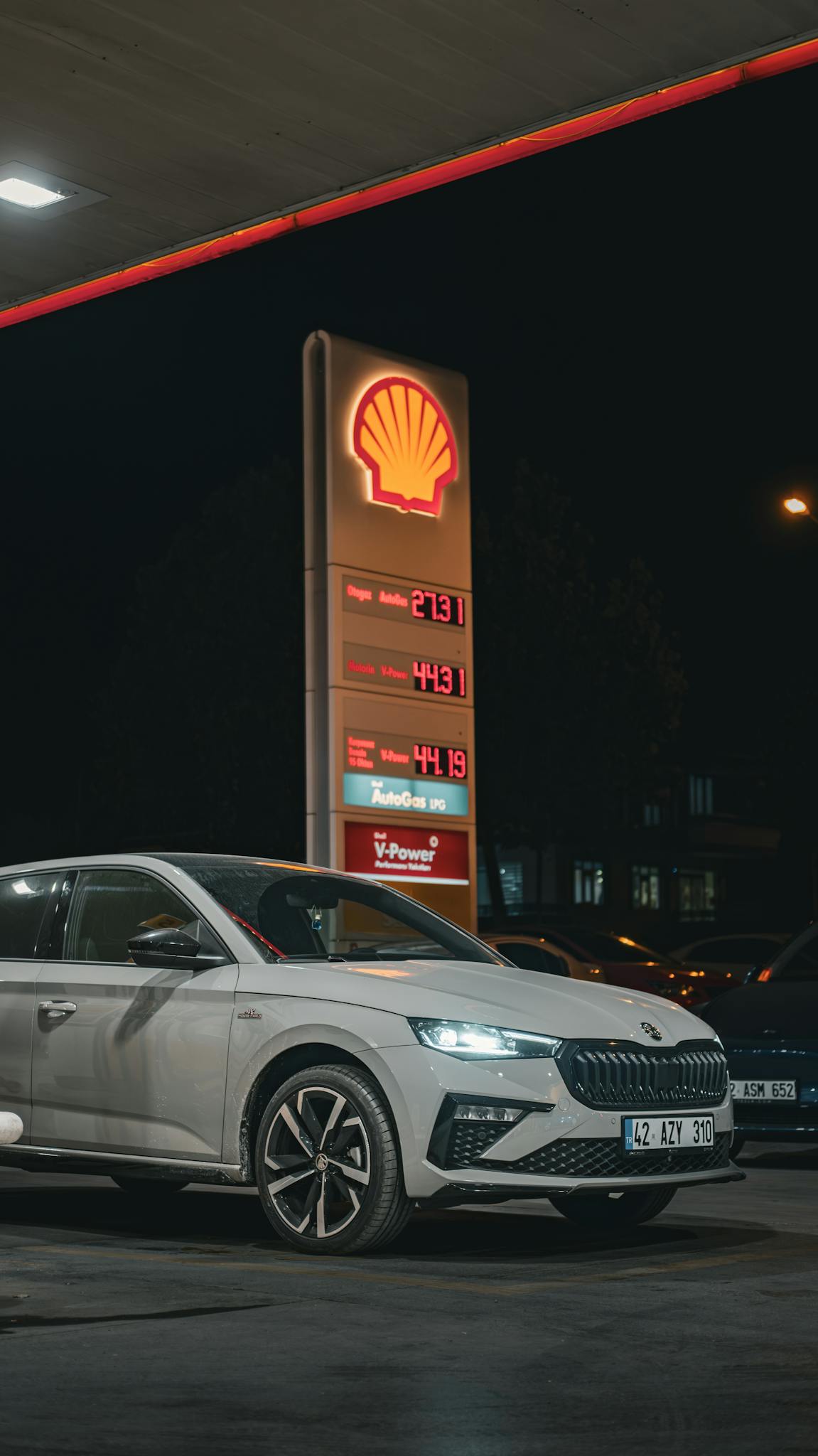 A sleek Skoda sedan parked at a Shell gas station during nighttime.