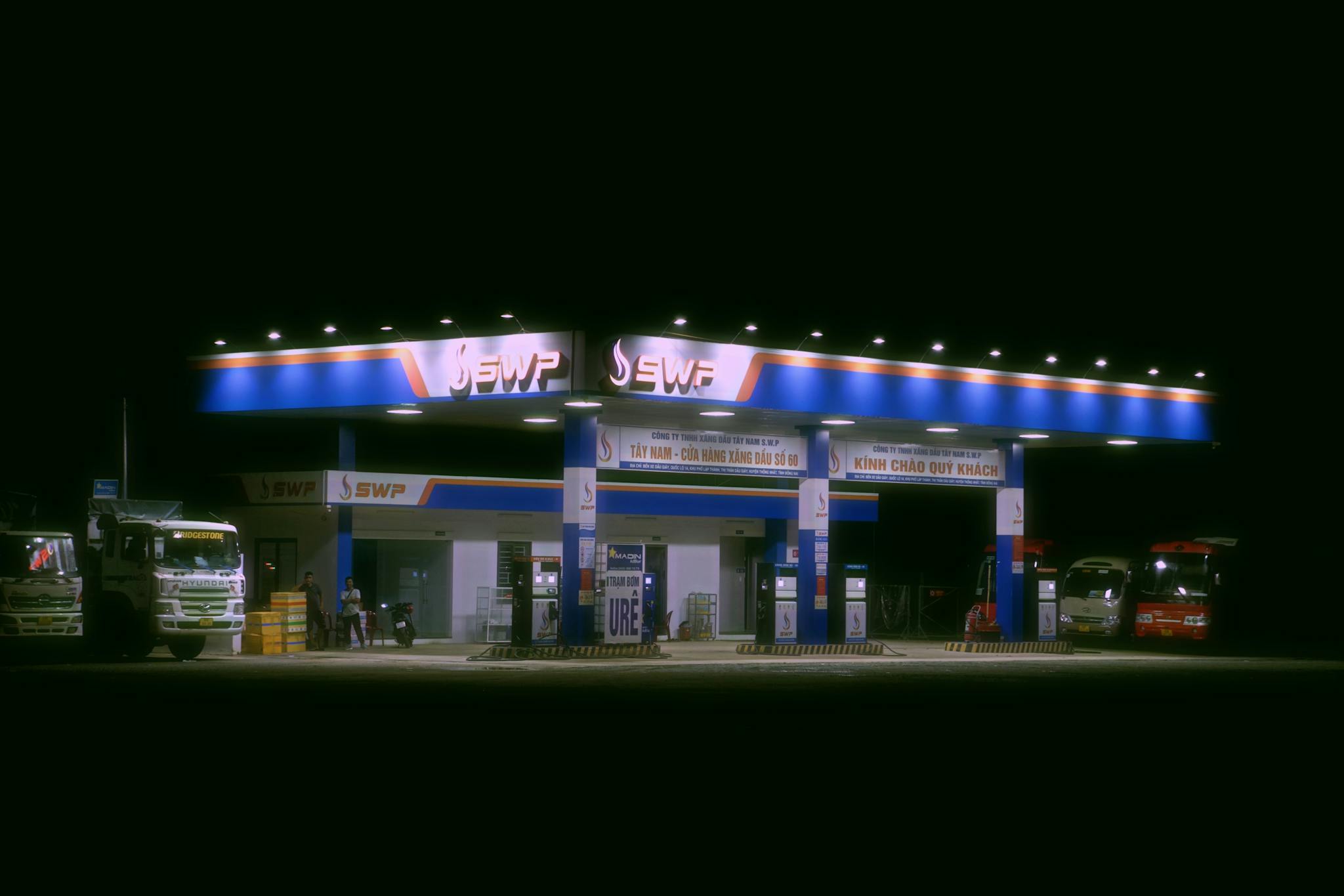 Nighttime view of a brightly lit gas station with trucks and cars parked.